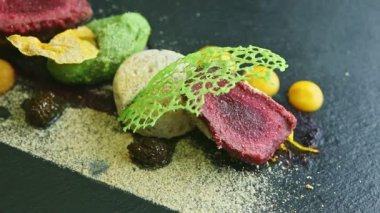 slow zoom out from finely decorated fried meat with assorted purees and sauces