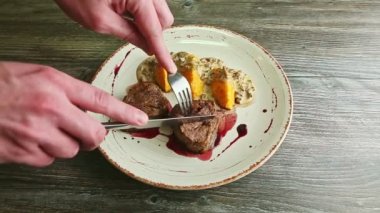 human hands cut off on half one piece of roasted meat by fork and knife