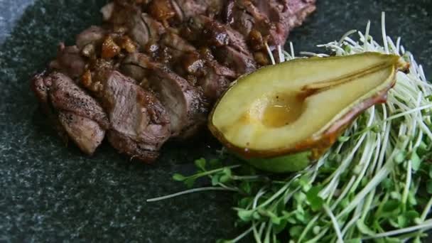 Zoom lento fuori dal piatto finemente decorato di fette di carne arrosto ruota su piatto nero — Video Stock
