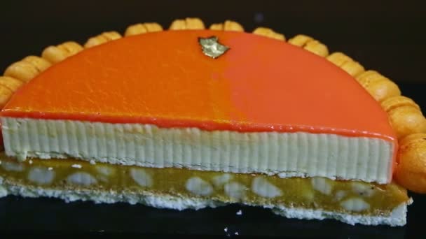 Panorama rapproché sur la moitié du gâteau au fromage orné de glaçure miroir orange — Video