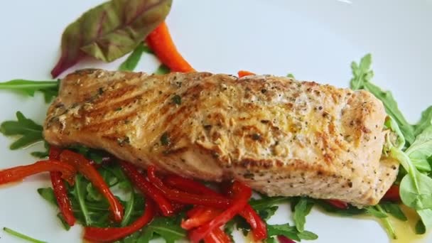Closeup grilled salmon on mixed salad spin around on white plate — Stock Video
