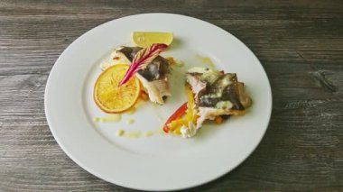 Beyaz tabakta krema sosuyla doldurulmuş yarım dilimlenmiş deniz balığına yakınlaştır.