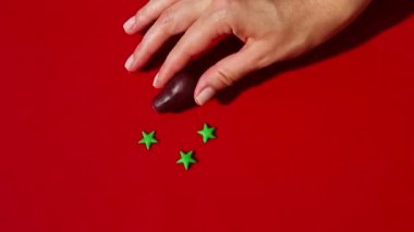 Kadın elinin üst görüntüsü badem ezmesi şekilli patlıcan şekeri yapmak için malzeme koyuyor.