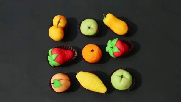 Top view on hand takes away fruit shaped marzipan candy from assortment — Stock Video