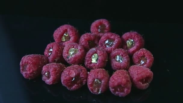 Foco fuera del grupo de frambuesas frescas rellenas con jalea mentira en negro — Vídeo de stock