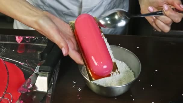 Gros plan confiseur décorer gâteau mousse glacée rose avec copeaux de noix de coco — Video