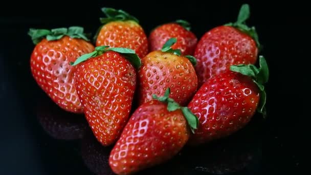 Foco fuera del grupo de fresas rojas jugosas frescas enteras mienten sobre fondo negro — Vídeos de Stock