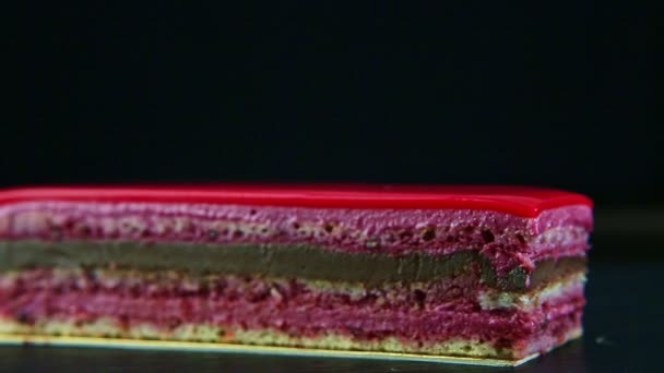 Closeup πανόραμα σε κομμάτι από ροζ τζάμια στρώσεις κέικ σοκολάτας με γέμιση μούρου — Αρχείο Βίντεο