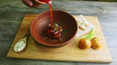 Kırmızı borş aslında ahşap tepside sunulan kile dökülüyor.