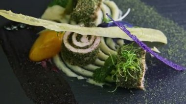 closeup finely decorated fish rolls with sauces spinning on black plate