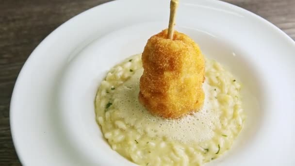 Closeup boiled barley porridge decorated with breaded whole pear rotates on plate — Stok video