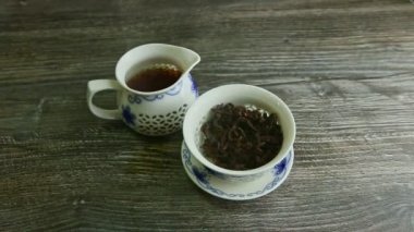 human hands take away cover from teapot stands next to kettle with tea