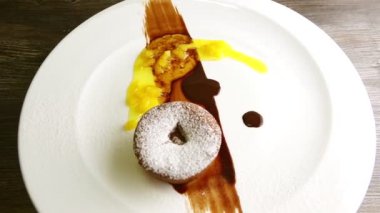 slow zoom in at sugar powdered small chocolate cake rotates on plate