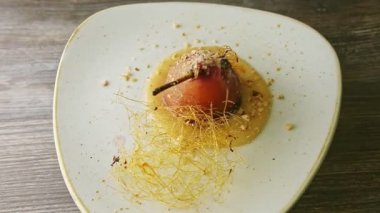 top view on baked pear finely decorated with caramel spirals spinning on plate