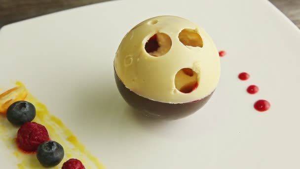 Slow zoom in at chocolate ball-shaped dessert rotates on white plate — Wideo stockowe