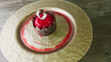 zoom in at red glazed dessert with castle shape chocolate rotates on golden plate