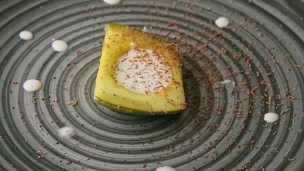 Slow zoom out from trendy decorated avocado dessert rotates on modern plate — Wideo stockowe