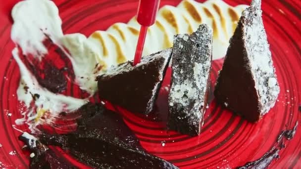 Closeup panorama on trendy decorated sliced brownie cake served on red plate — 图库视频影像