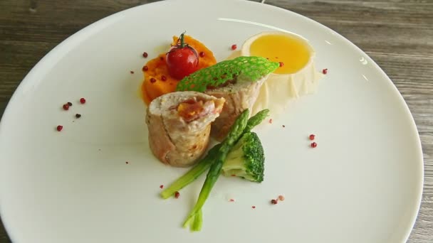 Slow zoom in at stuffed chicken roll with vegetables rotates on white plate — Stock Video