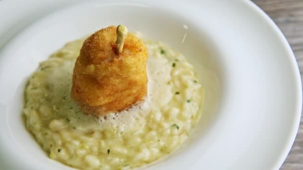 Zoom out from breaded whole pear on boiled barley porridge rotates on white plate — Stock Video