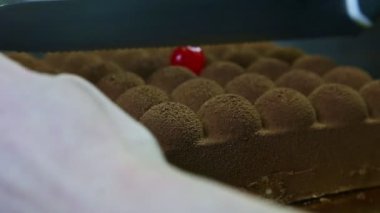 Yakın plan eller büyük bıçakla ikiye bölünmüş modern çikolatalı cheesecake.