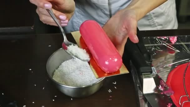 Closeup διαδικασία της διακόσμησης ροζ γλασαρισμένο κέικ μους με ροκανίδια καρύδας — Αρχείο Βίντεο