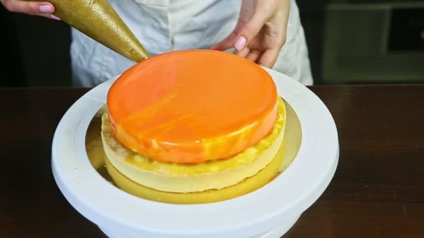 Proces zdobení tvarohového koláče s oranžovým zrcadlem glazura na bílém stojanu — Stock video