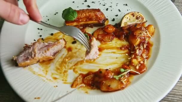 Closeup hand takes by fork piece from fried meat rib and puts in sauce — Stock Video