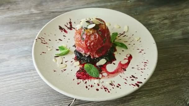 Exquisite decorated baked apple with syrup and nuts rotates on plate — Stockvideo