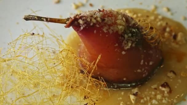 Closeup ολόκληρο αχλάδι εξαίσια διακοσμημένα με καραμέλα σπείρες κλώση στο πιάτο — Αρχείο Βίντεο