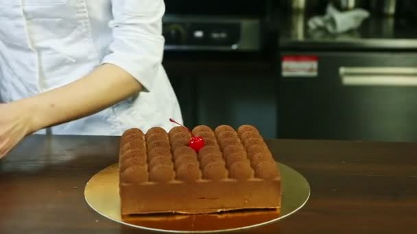 Confectioner show original creamy mousse cake with chocolate topping and cherry — Stockvideo