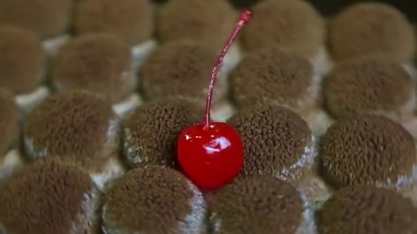 Closeup trendy shaped chocolate cake decorated with ripe cherry spinning around — Stock video