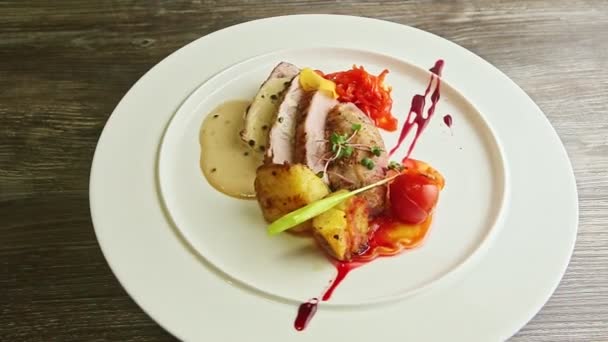 Медленное увеличение нарезанного жареного мяса и жареных овощей вращается на тарелке — стоковое видео