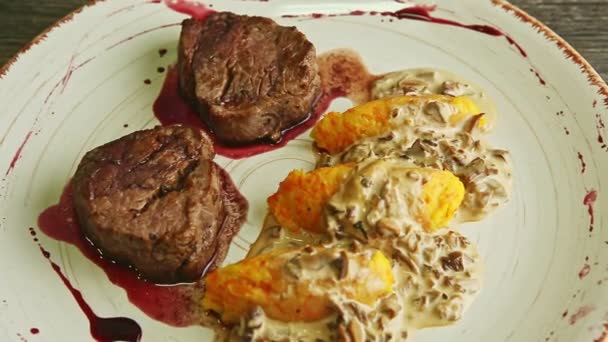 Closeup zoom in at finely decorated baked meat pieces with sauce and potato garnish — Stockvideo