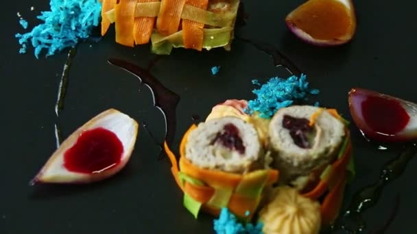 Closeup exquisite decorated stuffed meat vegetable rolls rotate on black plate — ストック動画