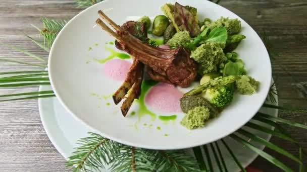 Hand rotates original plate with finely decorated roasted ribs and green vegetables — Stockvideo