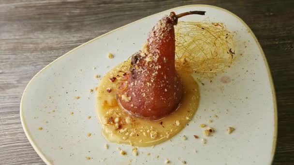 Delicious baked pear trendy decorated with caramel spirals spinning on plate — Stockvideo