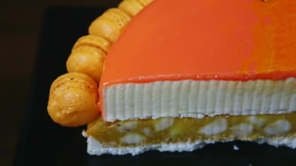 Closeup panorama on half of orange glazed cheesecake on almond interlayer — ストック動画
