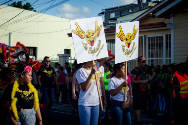 Concepcion De La Vega, DOMINICAN REPUBLIC - FEBRUARY 09, 2020: teenagers carry emblems of small group on city street at dominican annual carnival on February 9 in Concepcion De La Vega