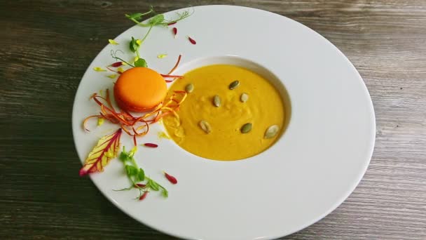 Human hand moves deep white with pumpkin cream soup with decoration — Stockvideo