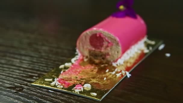 Closeup focus in and out from half of pink glazed mousse dessert with fruit filling — Stockvideo