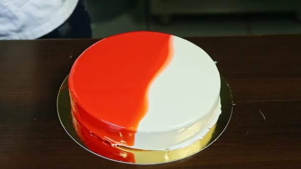 Vista superior sobre pastel de queso esmaltado entero rojo y blanco sobre soporte redondo dorado — Vídeo de stock