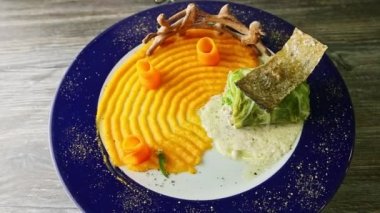 top view on finely decorated cabbage roll with yellow puree rotates on original plate