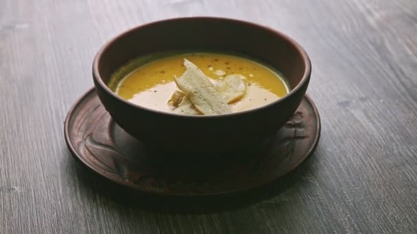Panorama down on yellow cream soup decorated with mushrooms and dried bread — 비디오