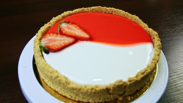 Focus in at whole round glazed cheesecake decorated with sliced strawberries — 图库视频影像