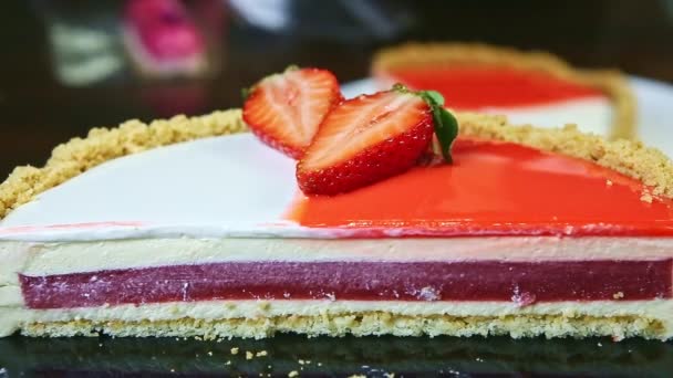 Slow panorama down at half of cheesecake with red jelly interlayer and colorful icing — Αρχείο Βίντεο