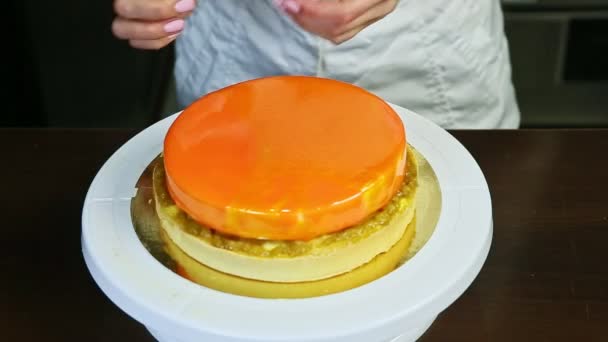 Confectioner decorate orange glazed round cheesecake with yellow mini macaroons — Stock video