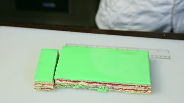Confectioner cut off by knife on portions green glazed creamy fruit layered cake — Αρχείο Βίντεο