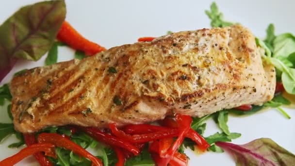 Макро вид жареного лосося на смешанном салате крутится на тарелке — стоковое видео