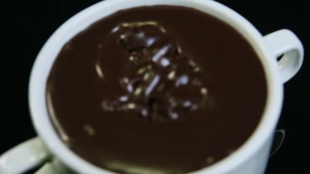 Top view closeup focus in at melted dark chocolate in big white round cup — Stockvideo